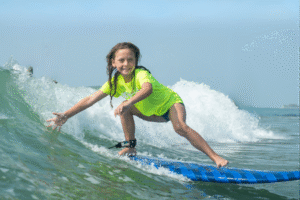 myrtle-beach-surf-lessons-camp child smiling and riding waves at myrtle beach surf lesson