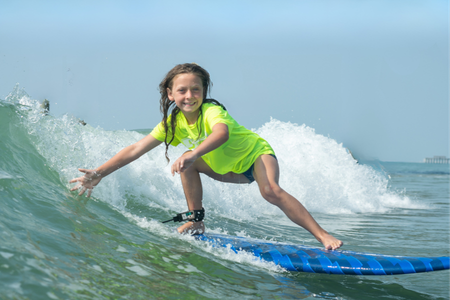 child smiling and riding waves at myrtle beach surf lesson