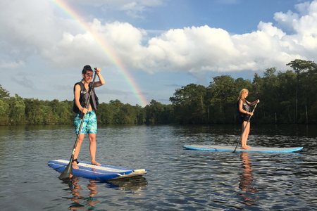 Two participants stand-up paddleboarding along Myrtle Beach shoreline